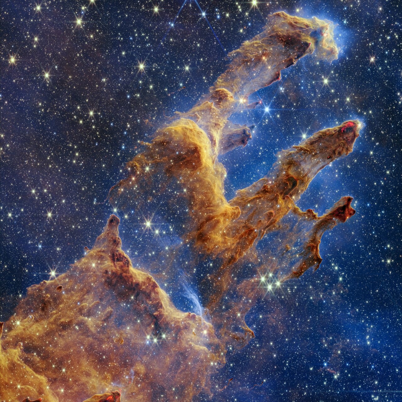 The Pillars of Creation: three tall columns of brown and orange gas against a field of stars